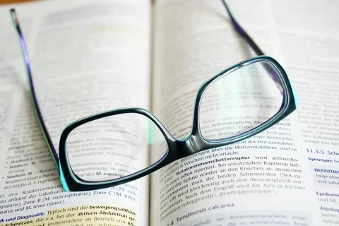 Reading glasses rest on top of a medical book.